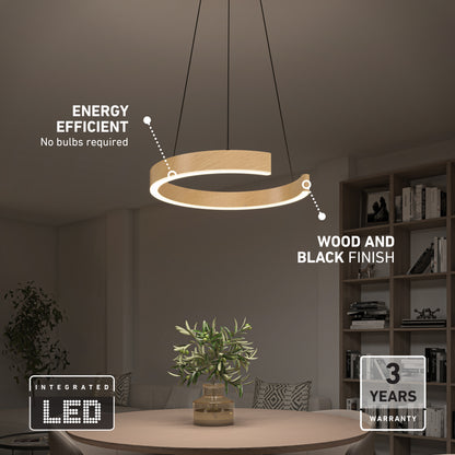 Modern circular pendant light with wood and black finish hangs over a dining table with a plant. Text highlights energy efficiency, integrated LED with no bulbs required, and a 3-year warranty. Shelves and books in the background.