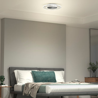 A modern bedroom features a gray bed frame, white bedding, teal and beige pillows, a beige throw, wooden nightstand and dresser, potted plants, and the Essence Disk LED flush mount by Artika-CAN-dev with a sleek chrome finish on the white ceiling.