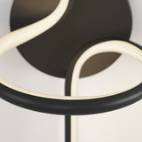 A close-up of a modern light fixture with smooth, curved black and white LED tubes against a neutral background. The design features loops and seamless lines.