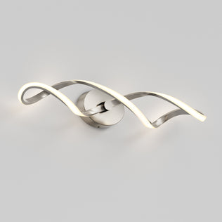 The Artika Swirl LED bathroom vanity light features two intertwined, wave-like metal strips, with one softly illuminated, all shown against a plain light gray background.