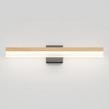 A modern wall-mounted light fixture with a horizontal wooden accent on top and a white illuminated bar below, attached to a rectangular black base against a plain light gray wall.