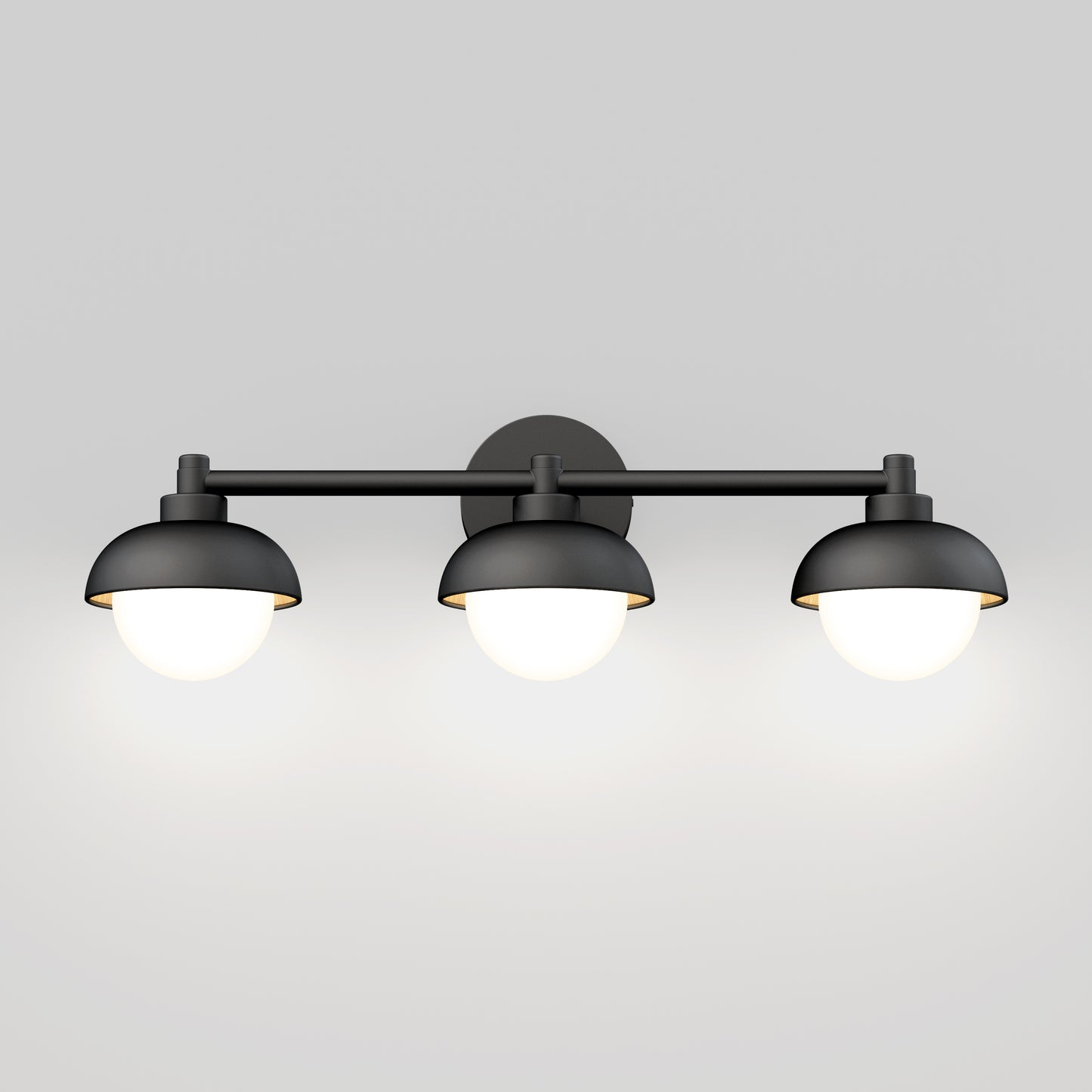 The Artika Boden LED mid-century bathroom vanity light features three black, dome-shaped shades with glowing white bulbs, wall-mounted against a plain light gray background.