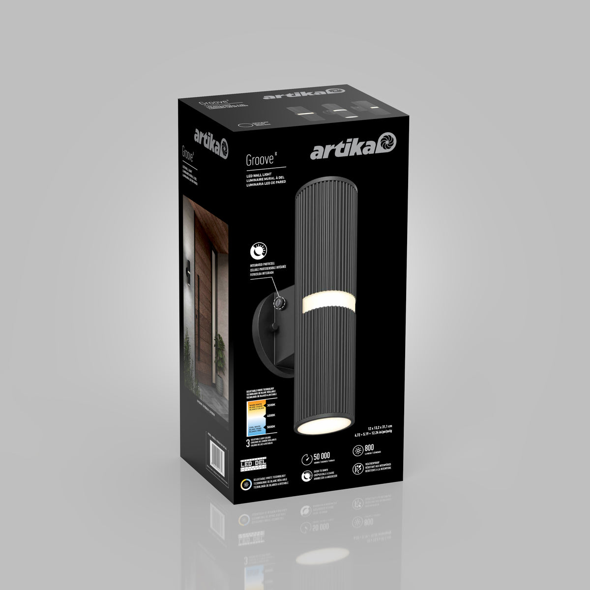 A black rectangular box for an Artika Groove wall light, featuring a photo of the cylindrical black fixture, LED details, and icons showing lighting specs. A side panel displays the lamp installed beside a doorway.