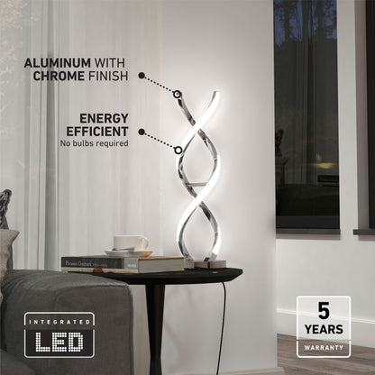Artika’s Swirl LED table lamp features a twisted double-helix design and aluminum chrome finish, offering energy efficiency and a 5-year warranty—shown on a black side table next to a white chair.
