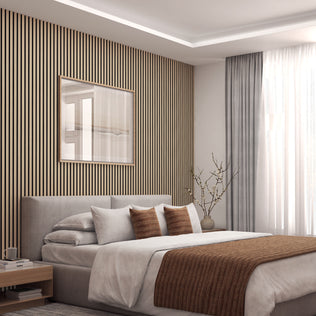 A modern bedroom featuring Artikas Sonolok sound-absorbing wall panel kit, a light gray bed with brown accent pillows and blanket, large window with sheer curtains, nightstand, and a minimalist vase with branches.
