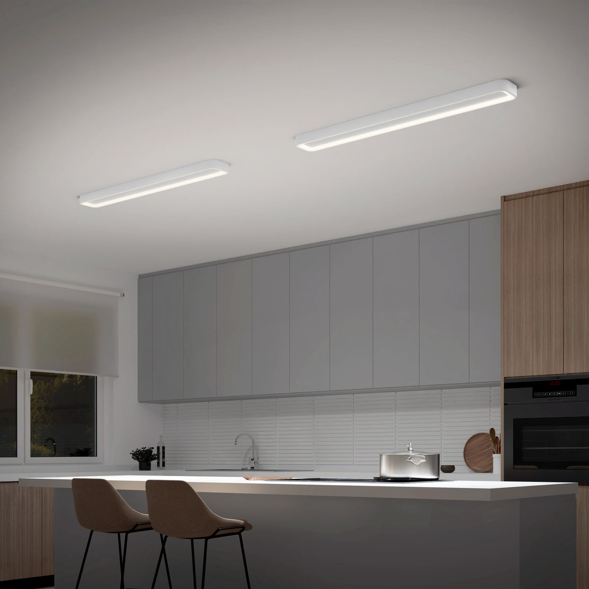 Modern kitchen with gray cabinets, wood accents, white countertop island, two beige barstools, and the Artika Aiden 48 in. LED modern flush mount light 5 CCT. Features include an oven, sink, window with white blind, and sleek rectangular fixtures.