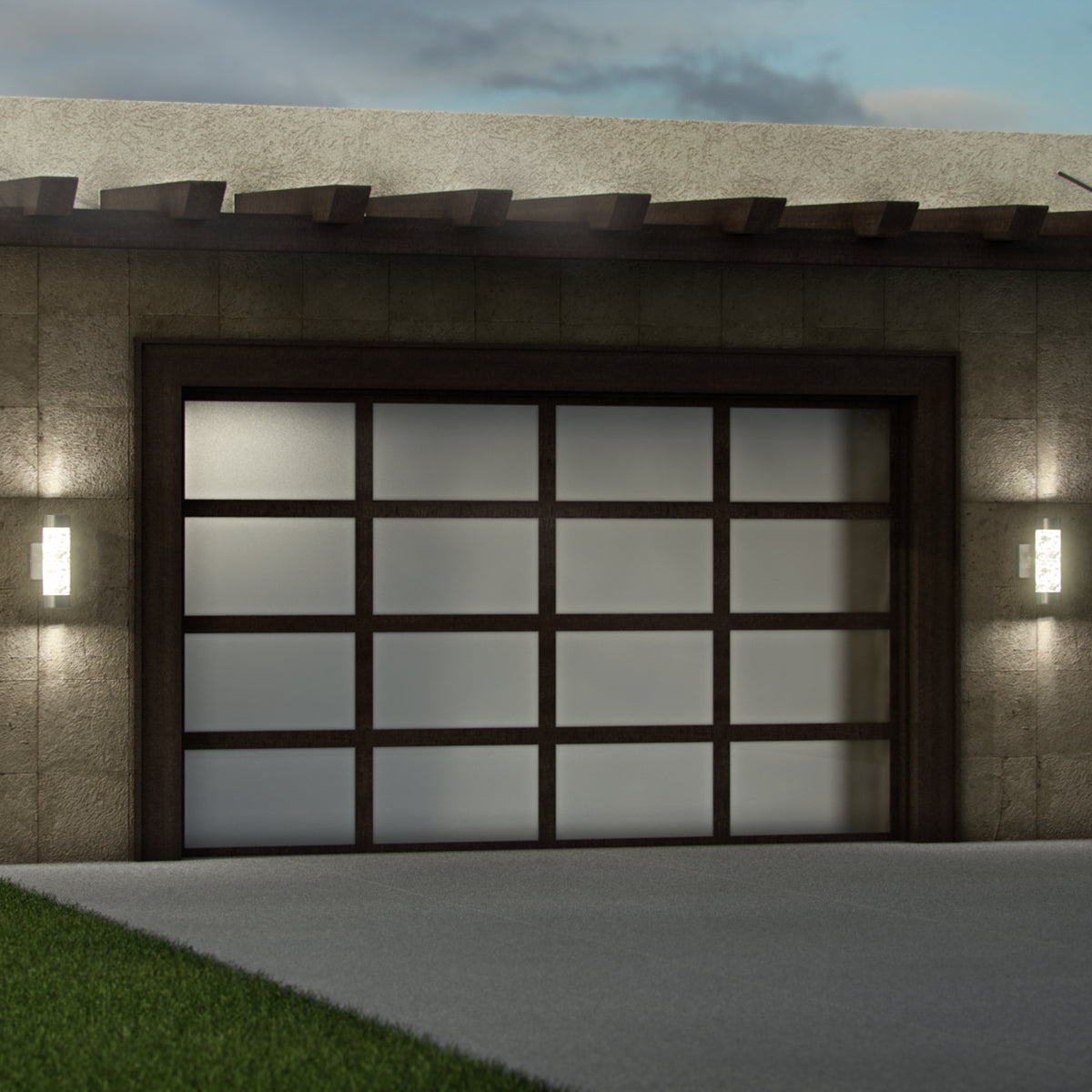 A modern garage door with frosted glass panels and a dark frame, flanked by two illuminated wall-mounted lights on a stone exterior, adjacent to a concrete driveway and a patch of grass.