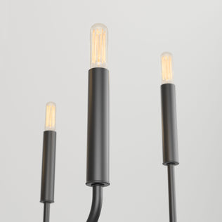 The Artika Manchester 6-light pendant features three modern black cylindrical fixtures with exposed filament bulbs, standing upright on a plain white background. The central fixture is in focus, while the others are slightly blurred.