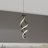 A modern pendant light with a twisted, spiral design hangs in front of gray kitchen cabinets and a light marble backsplash. The light features black and illuminated white elements intertwined.
