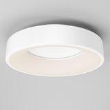 A modern, circular white ceiling light fixture with a minimalist design, mounted on a smooth, light gray ceiling. The light glows softly from the inner rim, creating an even, ambient illumination.