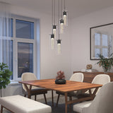 A modern dining room with a wooden table, four upholstered chairs, a bench, a potted plant, pendant lights, and a sideboard with décor, set against white walls and a large window with sheer curtains.