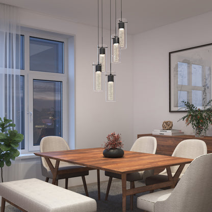 Modern dining room with a wooden table, four beige chairs, a bench, and the Artika Essence 5-light LED pendant above. A large window on the left lets evening light filter through sheer curtains; plants and framed artwork decorate the space.