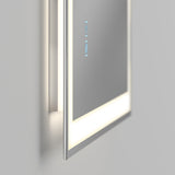 A close-up of a modern, rectangular mirror with built-in LED lighting and two illuminated touch buttons on the reflective surface, mounted on a light-colored wall.