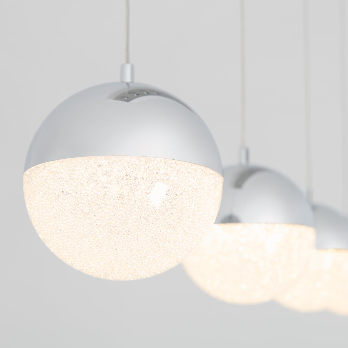 The Artika Sparkle 4-light LED pendant features four modern spherical lights with metallic tops and textured, glowing bottoms, hanging in a row against a plain light background for a bright, contemporary look.