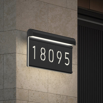 A modern illuminated house number sign displaying the numbers 18095 is mounted on a stone wall next to a dark vertical panel.