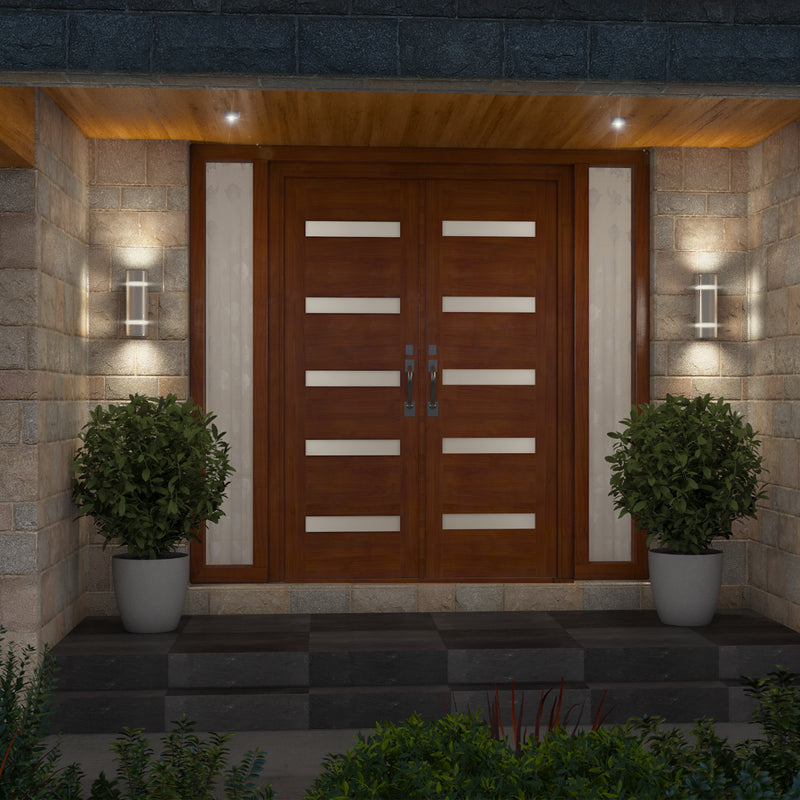 A modern wooden double front door with horizontal frosted glass panels is flanked by potted greenery and Artika’s Q1 indoor-outdoor wall lights, all set within a stone facade entryway.