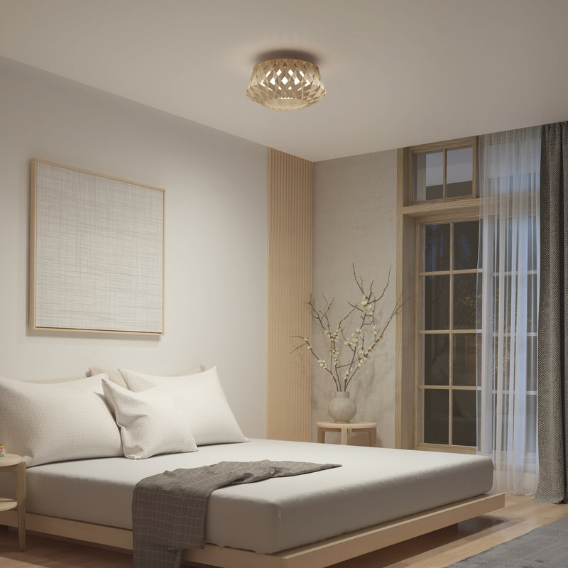 A minimalist bedroom features a low wooden bed, white bedding, and neutral decor. The Artika Kiran 13 in. modern LED flush mount light adds style overhead, while a vase with branches and framed artwork create calm serenity.