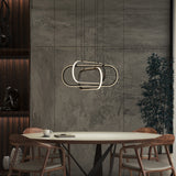 Modern dining area with a round table, four wooden chairs, a cup and saucer, decorative shelving, a potted plant, and a geometric pendant light hanging above the table, set against textured gray walls.