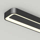 A close-up view of a modern, rectangular black ceiling light fixture with rounded edges, emitting a soft white glow. The fixture is mounted on a plain white ceiling.