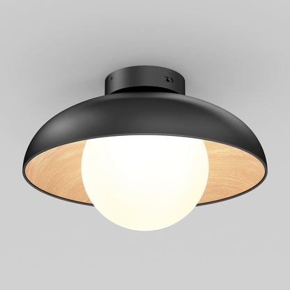 The Artika Boden LED flush mount light 5 CCT features a matte black outer shade, wooden inner lining, and a large frosted glass globe bulb, all mounted on a white ceiling for a modern look.