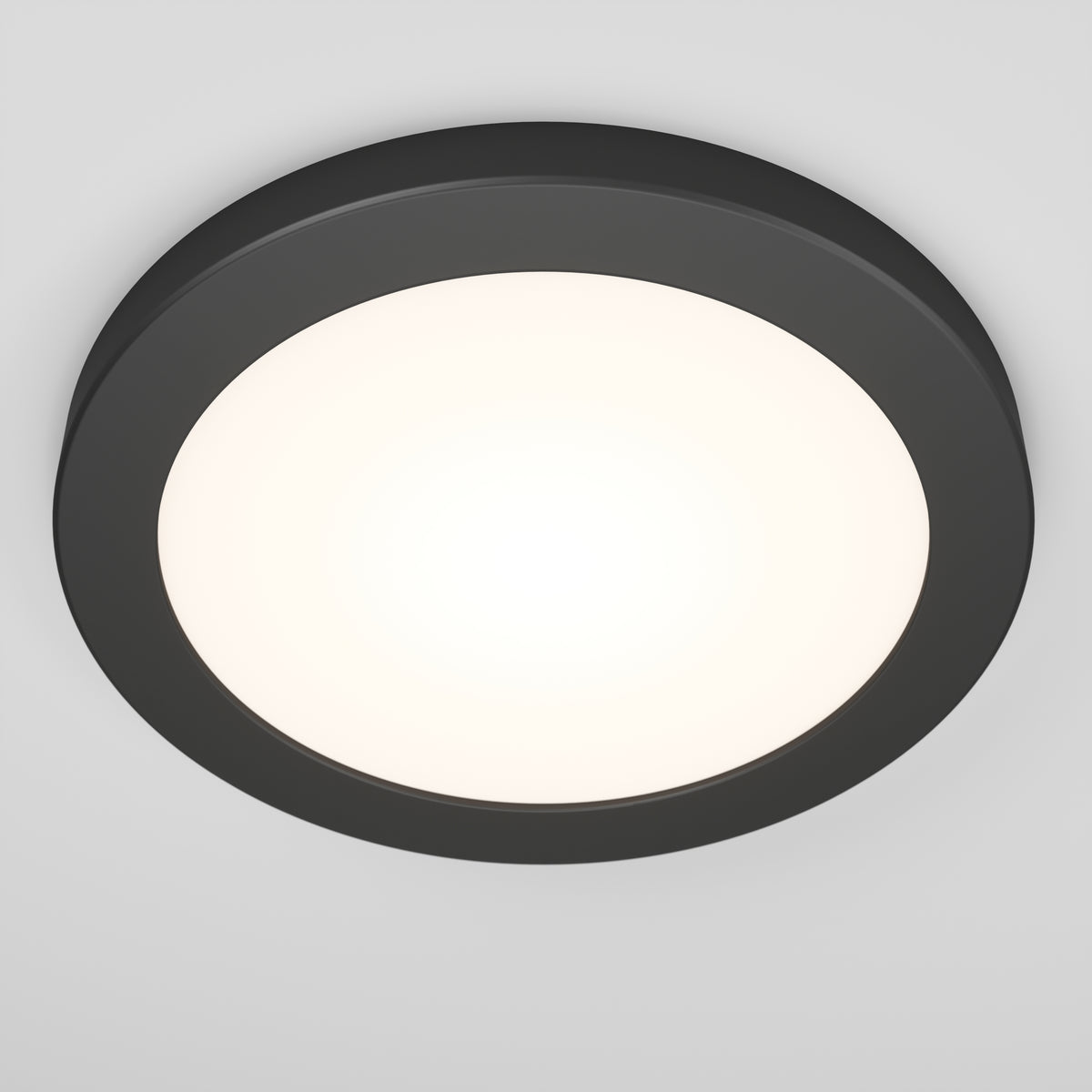 A round, modern ceiling light fixture with a black outer rim and a glowing white center, mounted on a white ceiling.