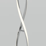A close-up of a modern, twisted LED light fixture with two intertwined, sleek, metallic arms against a plain light gray background.