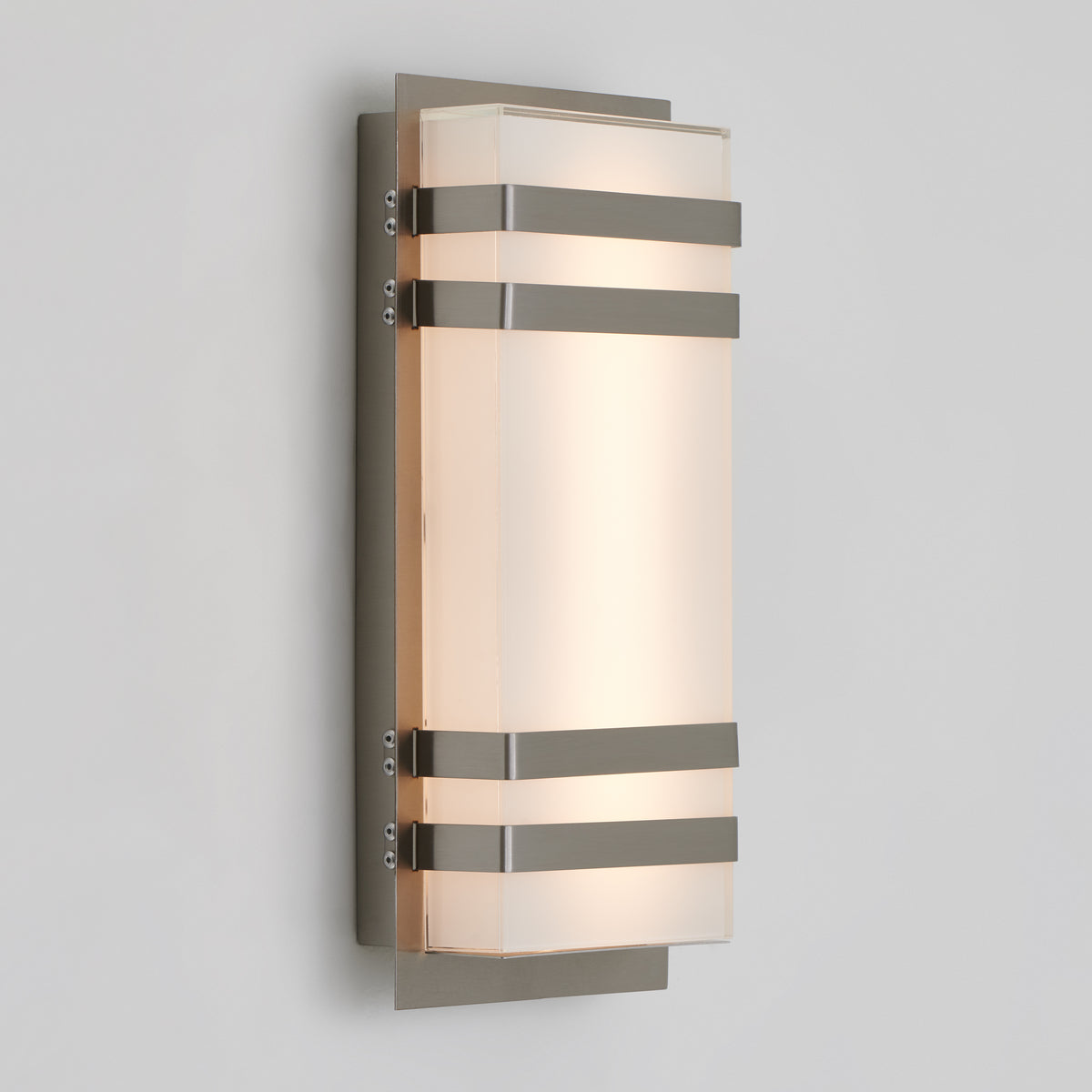 The Artika Glowbox 3 indoor-outdoor LED wall light features a frosted rectangular glass shade with three horizontal metal bands, mounted on a brushed metal plate against a white wall.