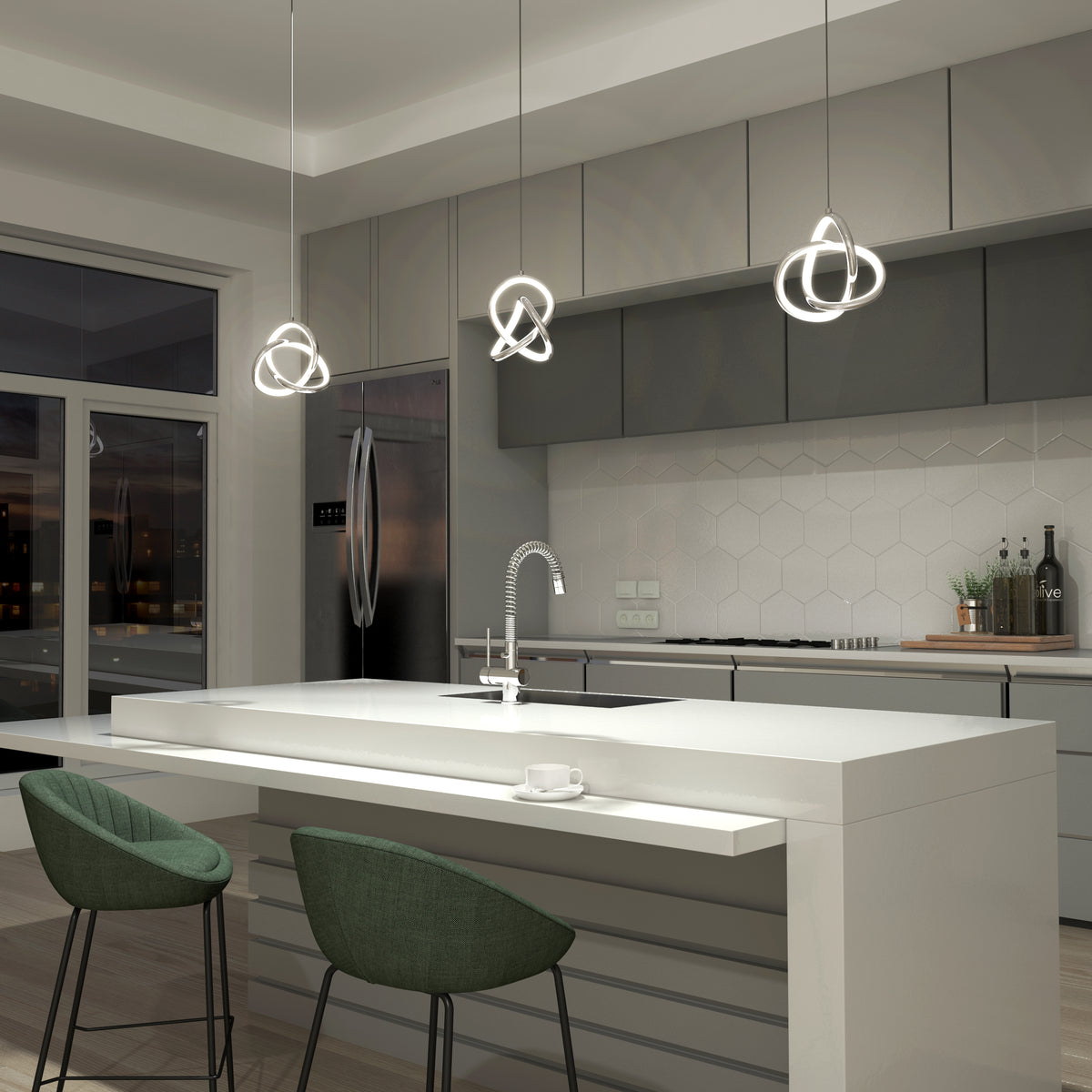 A modern kitchen with gray cabinets, a white island, green chairs, three geometric pendant lights, a stainless steel refrigerator, and hexagonal white backsplash tiles. A cup and saucer sit on the island.