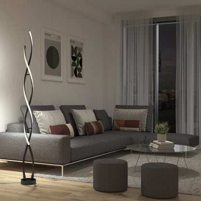 A modern living room with a gray sectional sofa, decorative pillows, two round ottomans, abstract wall art, a round coffee table, sheer curtains, a large window, and the Artika Swirl modern LED floor lamp.