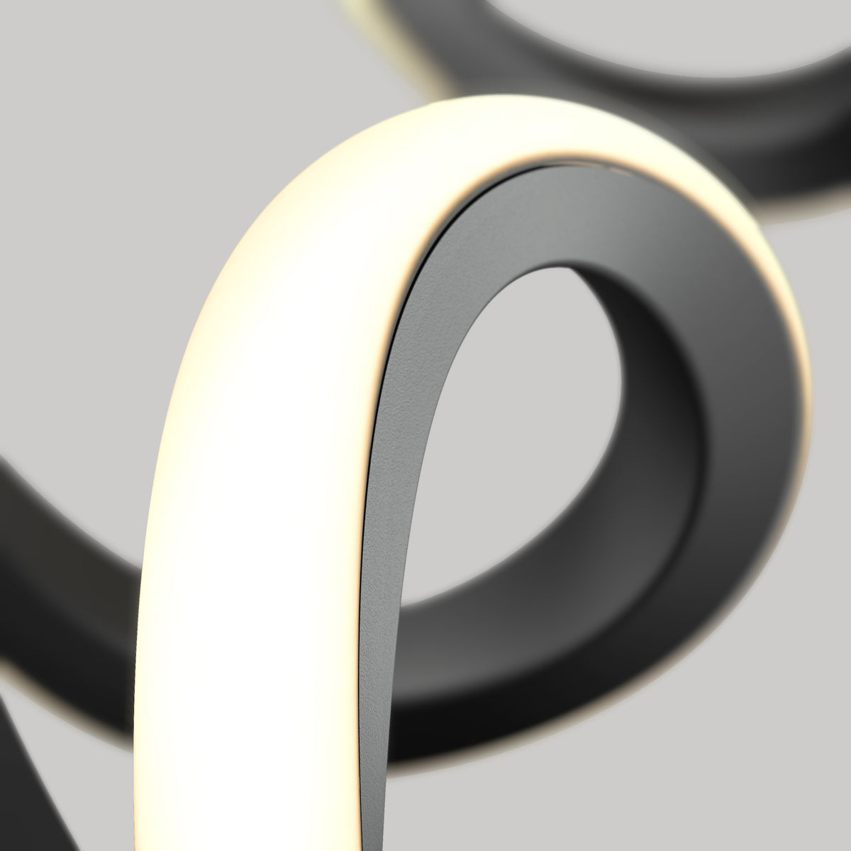A close-up of a modern, abstract light fixture featuring a smooth, looping black and white band emitting a soft, warm glow against a neutral gray background.