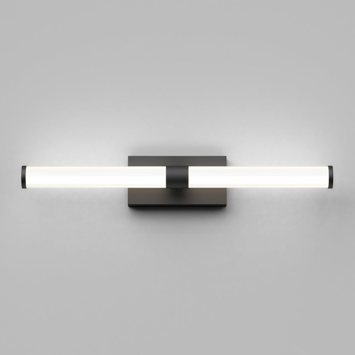 A modern wall-mounted light fixture with a horizontal cylindrical frosted glass shade, emitting a soft glow, attached to a square metallic base against a light gray wall.