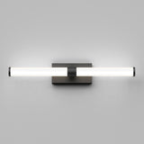 A modern wall-mounted light fixture with a horizontal cylindrical frosted glass shade, emitting a soft glow, attached to a square metallic base against a light gray wall.