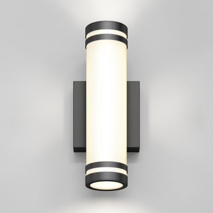 A modern cylindrical wall sconce with a frosted white diffuser and dark metallic end caps, mounted on a rectangular backplate, emits light upward and downward against a plain light gray wall.