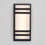 A rectangular wall sconce with a frosted glass center, framed by a black metal border and two horizontal black metal bars. The light glows softly against a plain, light-colored wall.