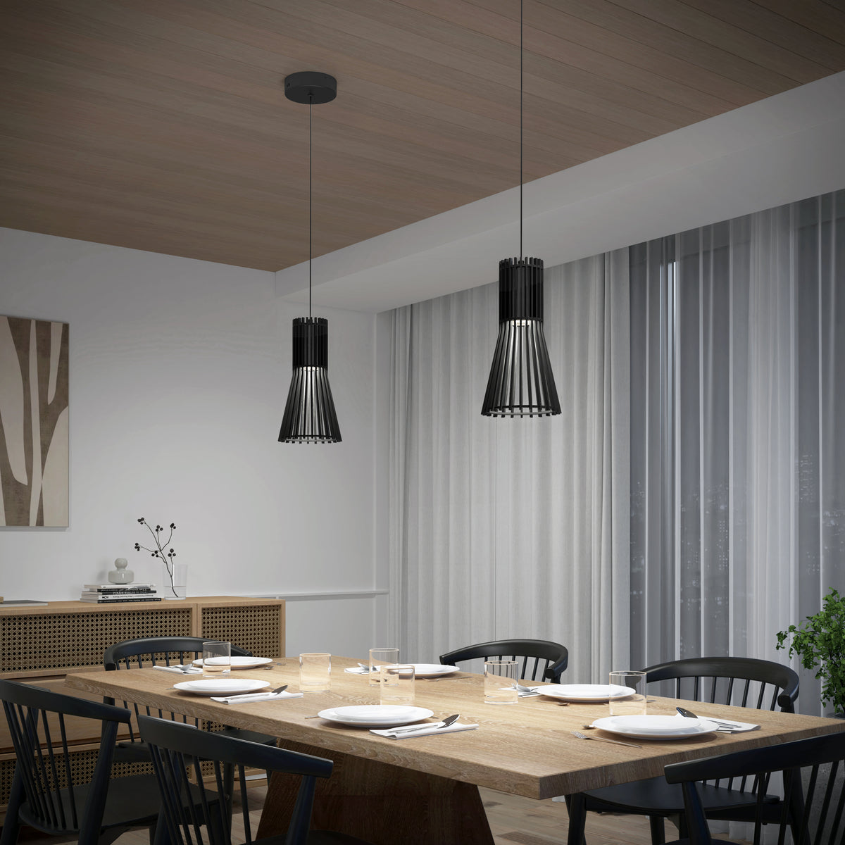 A modern dining room with a wooden table set for six, black chairs, two black pendant lights, sheer curtains, and minimalist decor including a sideboard and abstract wall art.