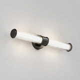 A modern wall-mounted light fixture with a cylindrical, horizontally-oriented glass shade and a black metal base, emitting soft light against a plain gray background.