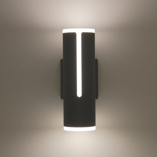 The Artika Linea modern indoor-outdoor LED wall light features a cylindrical black design with vertical cutouts, casting soft white light both upward and downward on any wall.