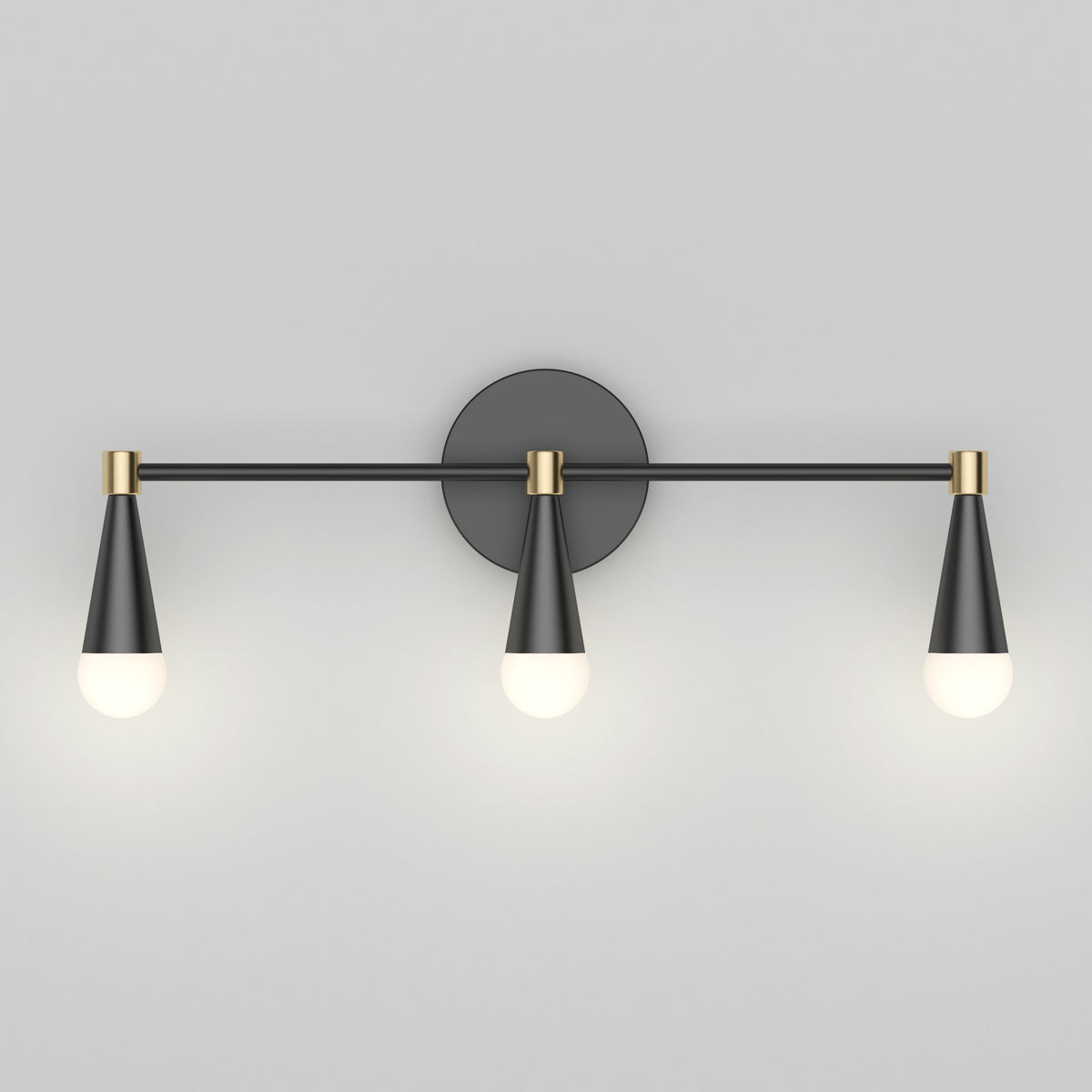 A modern wall sconce with three black and gold cone-shaped light fixtures, each holding a round white bulb, mounted on a flat, light gray wall.