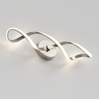 The Artika Swirl LED bathroom vanity light features two intertwined, curved metal strips—one illuminated and one metallic—mounted on a circular base against a light gray background.
