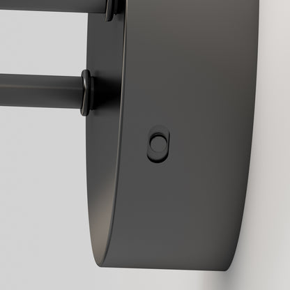 Close-up of the Artika Finley LED modern bathroom vanity light 3 CCT, featuring a matte black, wall-mounted design with a circular base and side button, set against a light-colored wall.
