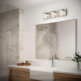 Modern bathroom with a large mirror, wood vanity, white countertop, a vase of flowers, marble shower with glass door, and the Artika Crystal Cube LED bathroom vanity light 5 CCT mounted above the mirror.