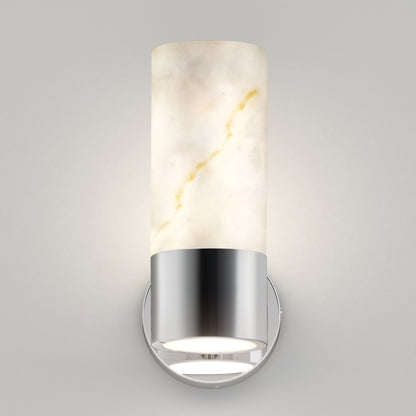 The Artika Marble LED contemporary sconce 5 CCT features a cylindrical frosted glass shade with subtle veining and a chrome base, casting soft warm light on a plain light gray wall.