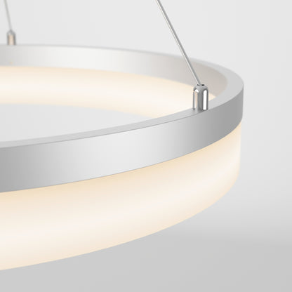 Close-up of Artika’s Optical LED pendant light 3 CCT, featuring a modern circular design with a white frame and frosted diffuser, suspended by metal cables and glowing softly against a light gray background.