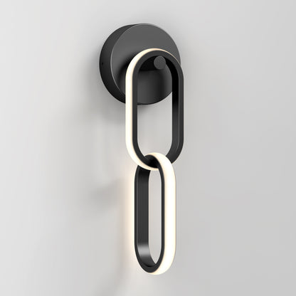 The Artika Catena modern LED wall sconce 5 CCT features two interlocking oval LED rings in black and white on a round black base, shown mounted on a plain light gray wall.