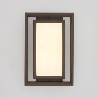 The Artika Ghost indoor-outdoor LED wall light features a frosted panel framed by a dark metal border, mounted on a light gray wall.