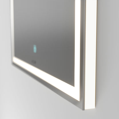 Close-up of the Artika Emeraude dimmable LED mirror 3 CCT, a modern rectangular mirror with built-in edge lighting and a blue touch button, mounted on a white wall and emitting soft, even light.