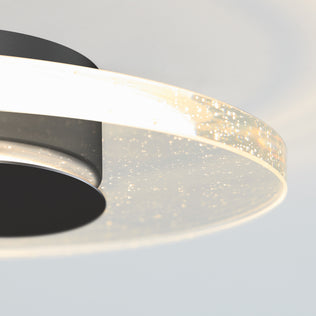 Close-up of Artikas Essence Disk LED flush mount, featuring a circular glowing rim and embedded bubbles that create a sparkling effect against a soft white background.