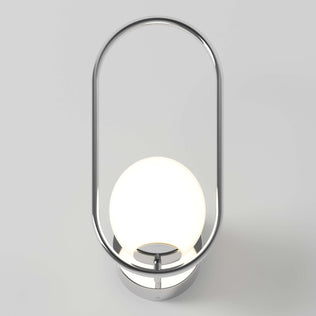 The Artika Bloom LED Sconce 3 CCT features a modern chrome oval frame encircling a glowing white spherical bulb, all mounted on a round base against a light gray background.
