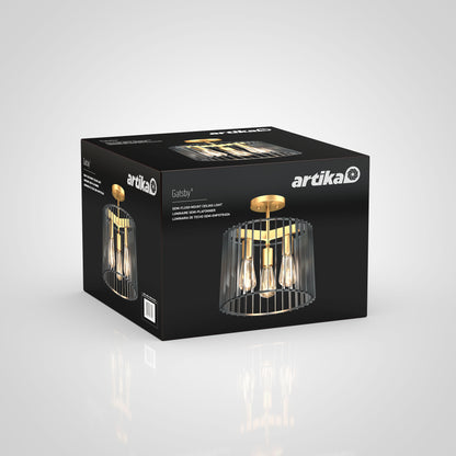 A black Artika box displays the Gatsby flush mount light, a modern gold and black ceiling fixture with exposed bulbs and a metal cage design. The packaging shows the brand name and product details.