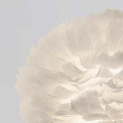 The Artika Plume LED pendant light features white feathers softly illuminated against a pale gray background, creating a delicate and airy look.